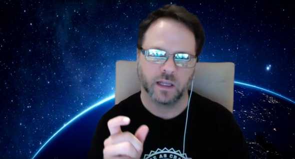 Screenshot of me teaching in a zoom video conference with a background that looks like space. I've got my head slightly tilted and I'm reaching toward the screen with my right hand, thumb and forefinger in a position like I'm holding something. But I'm not.