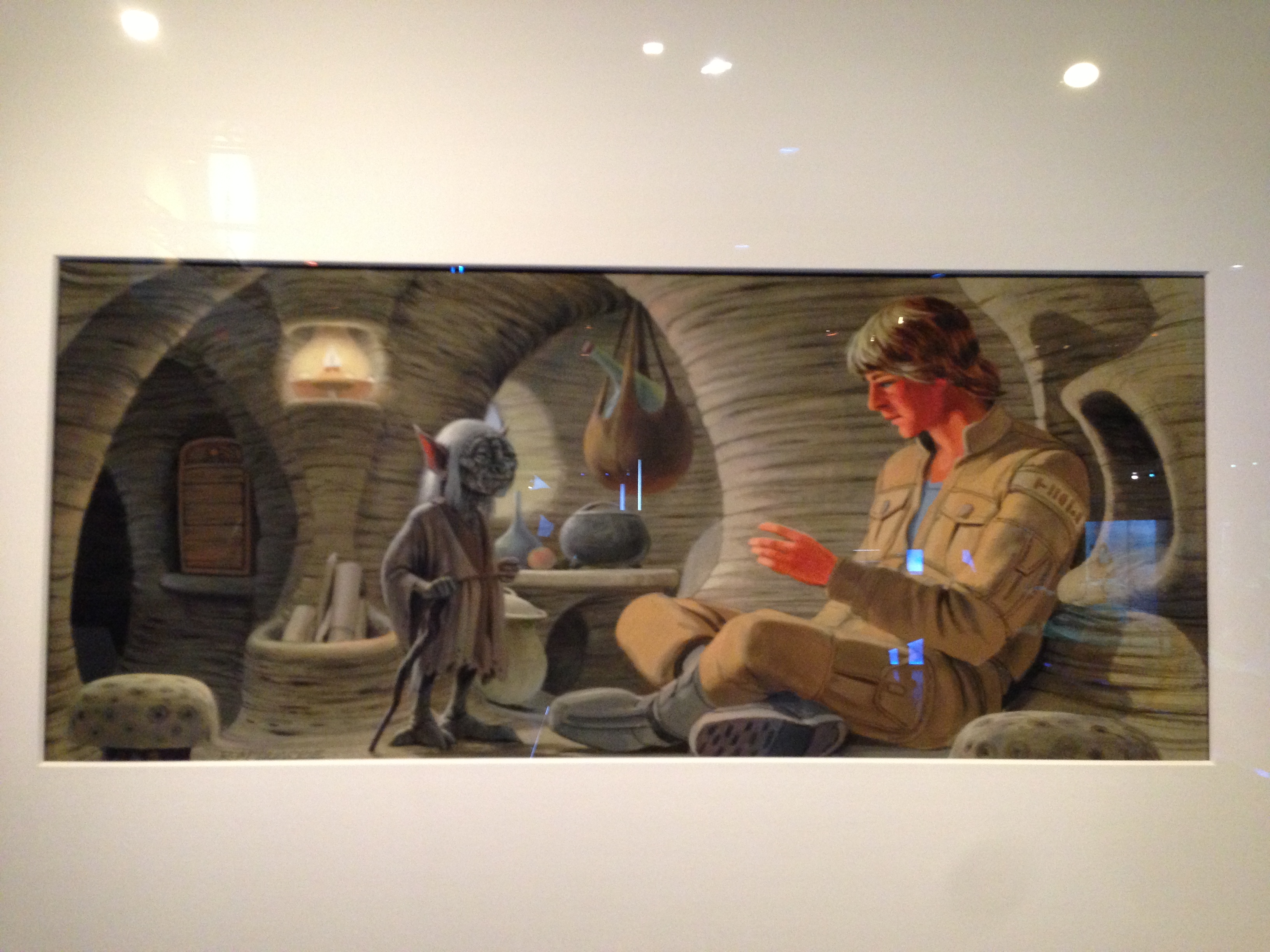 Ralph McQuarrie’s production painting of the same scene: Yoda standing in the curved, woven-walled Dagobah hut with a lantern glowing behind him and a gourd hanging from the ceiling, while a young Luke in tan fatigues sits cross-legged at the right — full colour and texture, but no camera or interaction notes.