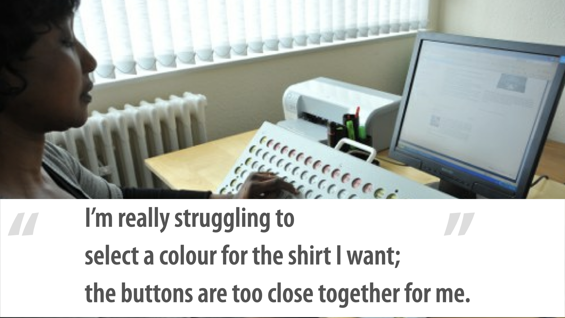 Photo of a woman typing with one finger on a large keyboard whose keys are recessed below the surface and spaced well apart; she rests her forearm on the board as she works, a monitor on the desk. Caption: ‘I’m really struggling to select a colour for the shirt I want; the buttons are too close together for me.’